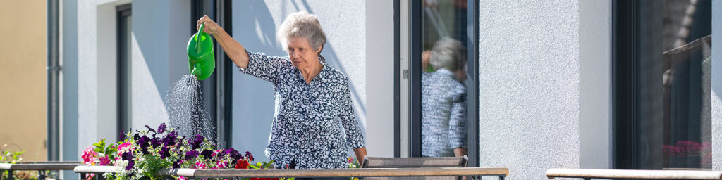 Frau gießt auf dem Balkon des Ricam Hospiz Zentrums Blumen