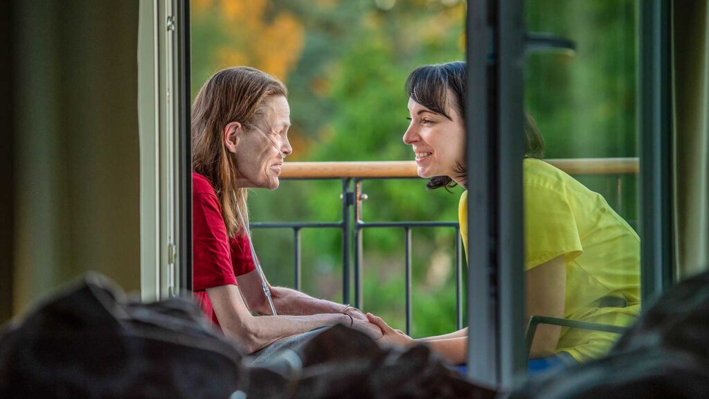 Sterbebegleitung Sterbebegleitung, zwei Frauen sitzen sich in einem Hospiz auf einer Terrasse gegenüber